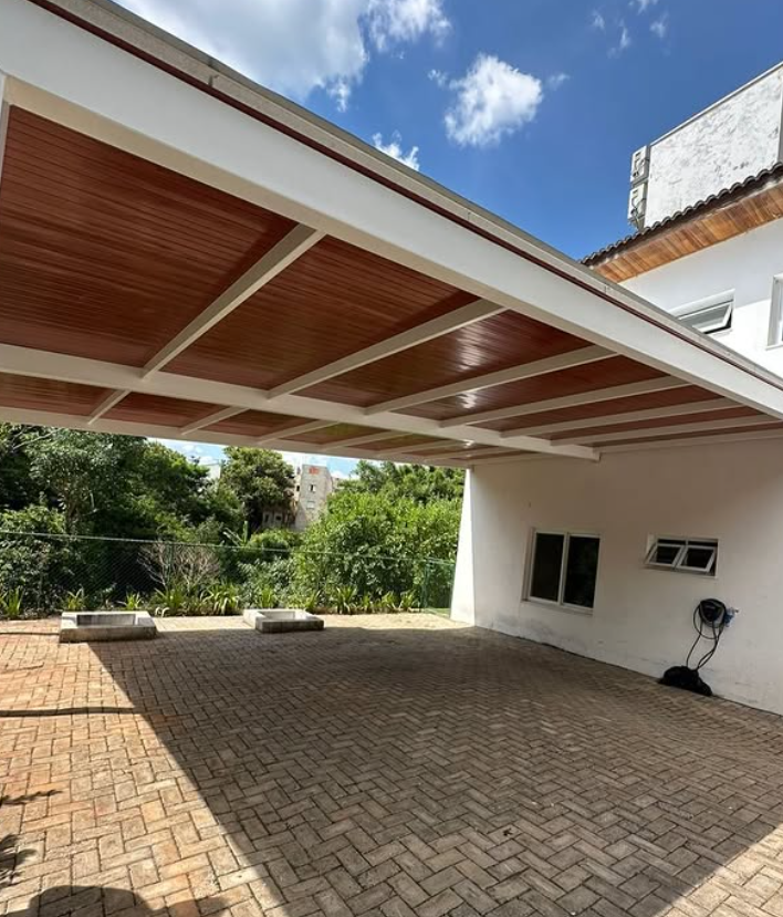 Cobertura metálica com forro amadeirado em área de garagem
